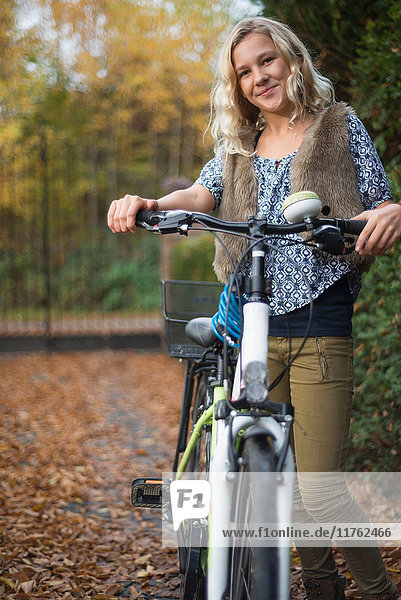 Porträt eines Mädchens mit Fahrrad in der Hand im Herbstpark