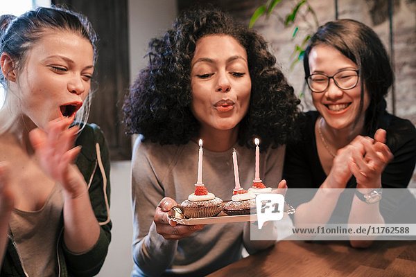Frau bläst Kerzen auf Geburtstagskuchen aus