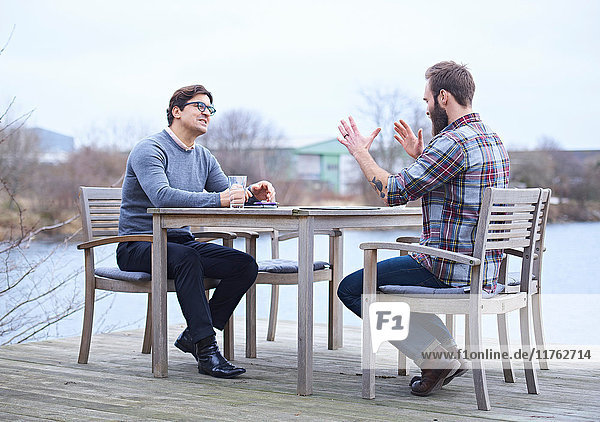 Zwei männliche Designer diskutieren am Wasser vor dem Designstudio