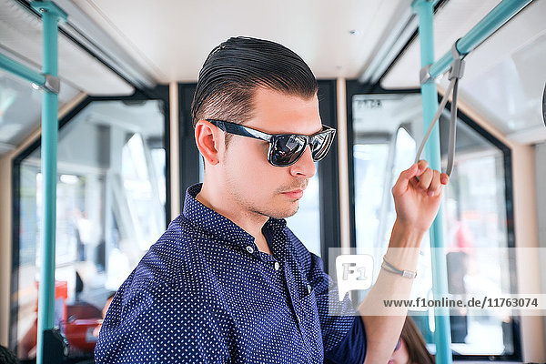 Junger Mann mit Sonnenbrille im Bus