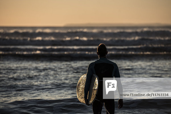 Ein Surfer  der die Wellen am Croyde Beach in Devon  England  Vereinigtes Königreich  Europa betrachtet