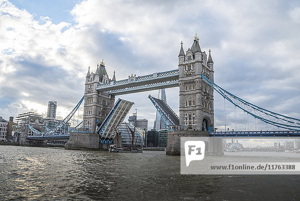 Tower Bridge angehoben mit einem großen Schiff  das die Brücke passiert  mit dem Londoner Rathaus und dem Shard im Hintergrund  London  England  Vereinigtes Königreich  Europa