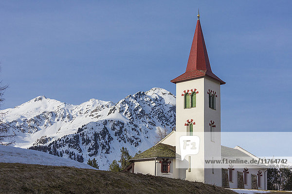 Die weiße Alpenkirche umrahmt von verschneiten Gipfeln  Maloja  Bergell  Kanton Graubünden  Engadin  Schweiz  Europa