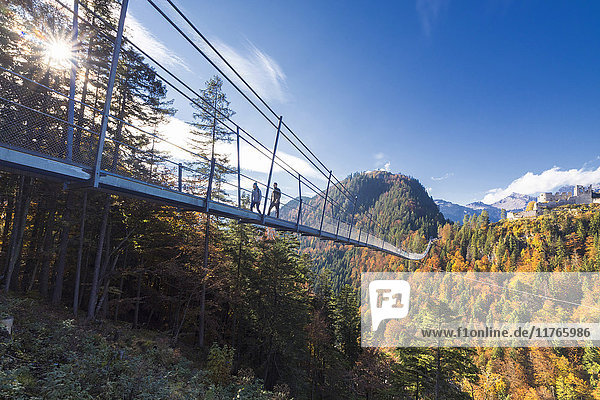 Tourists on the suspension bridge called Highline 179 framed by colorful woods in autumn Ehrenberg Castle Reutte Austria Europe