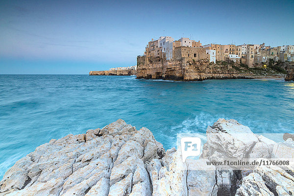 Türkisfarbenes Meer in der Abenddämmerung  eingerahmt von der auf den Felsen thronenden Altstadt  Polignano a Mare  Provinz Bari  Apulien  Italien  Europa