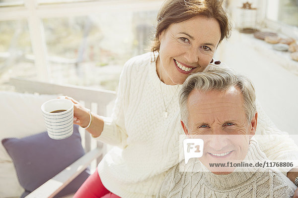 Portrait smiling mature couple hugging and drinking coffee