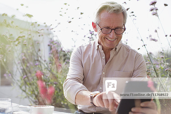 Smiling senior man using digital tablet on patio