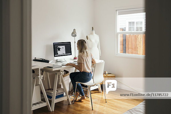 Full length rear view of graphic designer using computer at home
