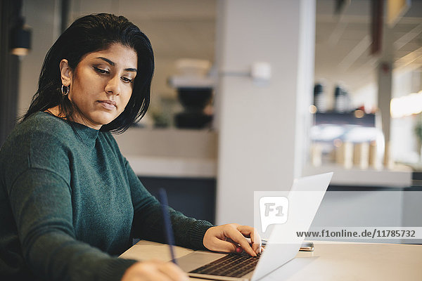 Geschäftsfrau beim Schreiben mit dem Laptop am Schreibtisch im Büro