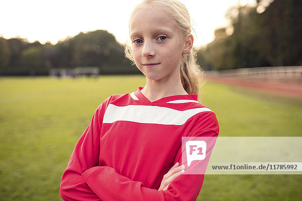 Porträt eines selbstbewussten Mädchens mit verschränkten Armen auf dem Fußballfeld