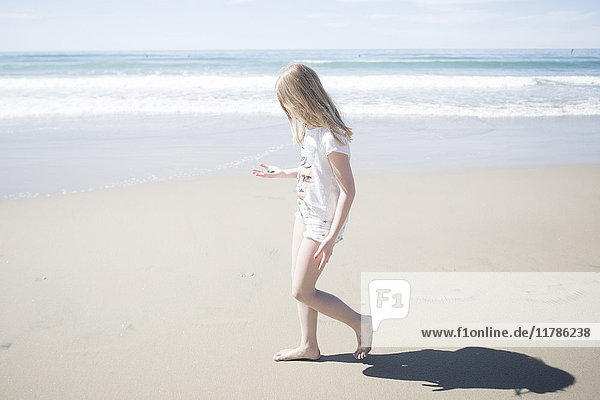 Seitenansicht des Mädchens mit Stein beim Spaziergang am Strand