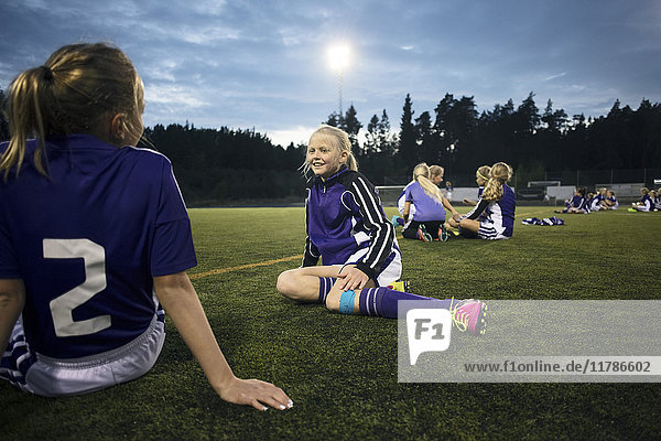 Mädchen entspannen sich auf dem Fußballplatz gegen den Himmel