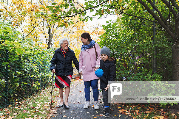 Full length of happy senior woman walking with daughter and great grandson in park