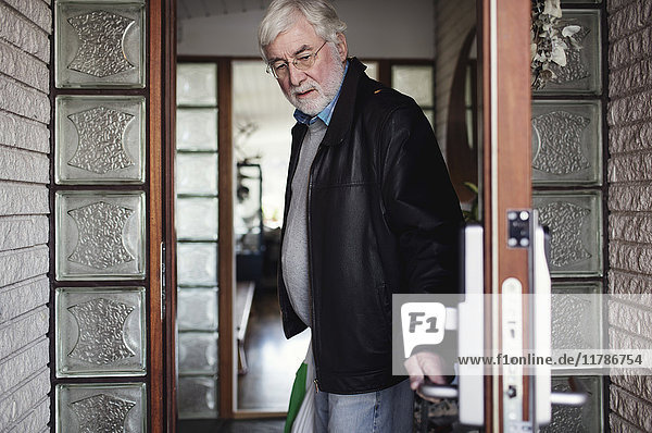 Senior Mann mit Lederjacke und schliessender Tür