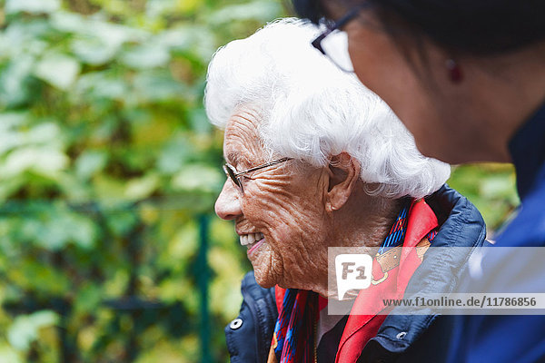 Seitenansicht der glücklichen Seniorin mit Hausmeisterin im Park