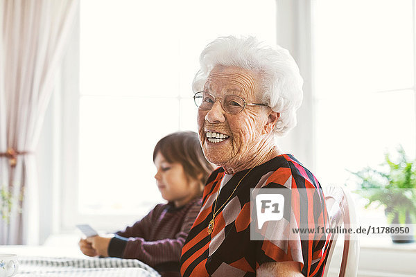 Porträt einer glücklichen älteren Frau  die mit einem Urenkel zu Hause sitzt und Karten spielt.