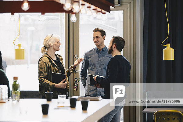 Businesswoman discussing with male colleagues in brightly lit office
