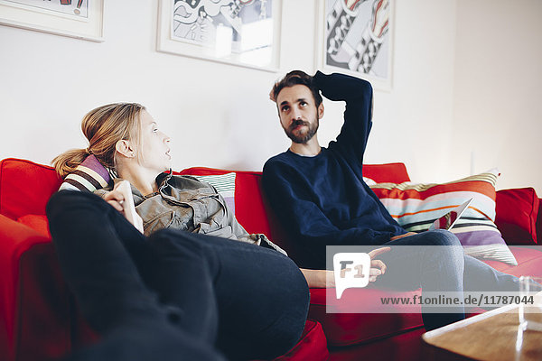 Couple talking while relaxing on sofa at home