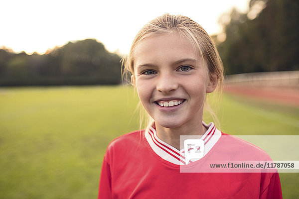 Portrait of happy female athlete standing on soccer field
