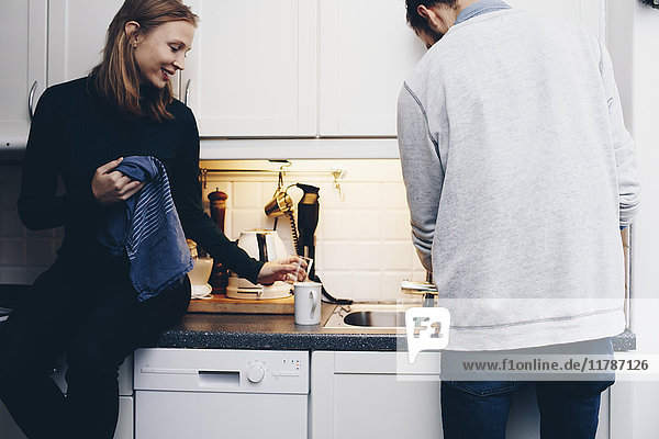 Couple washing dishes in kitchen at home