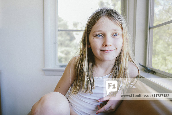 Thoughtful girl sitting on sofa by window at home