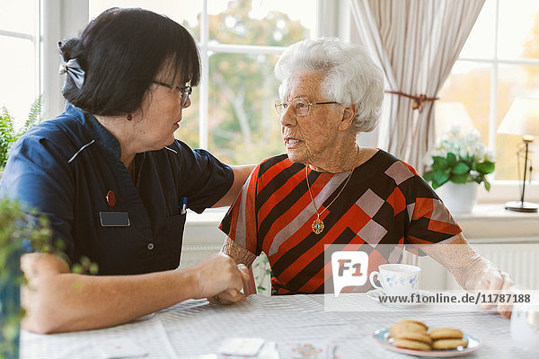 Female caretaker consoling senior woman at nursing home