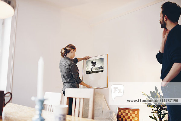 Man looking at woman holding painting frame at home