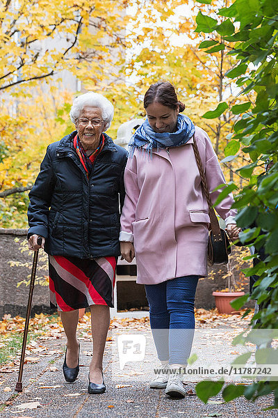 Volle Länge der älteren Frau  die mit der Tochter im Park läuft.