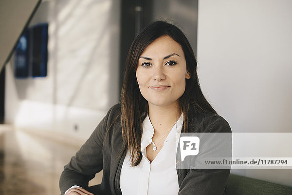 Portrait of confident businesswoman sitting on sofa at office lobby