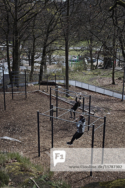 High angle view of athletes hanging from monkey bars in forest