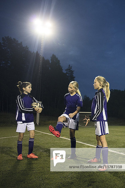 Mädchen  die nachts auf dem Fußballfeld gegen den Himmel stehen.