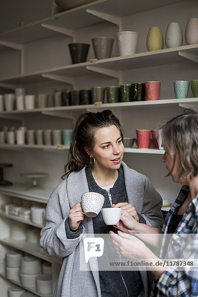 Töpferinnen diskutieren mit Kaffeetassen in der Keramikwerkstatt