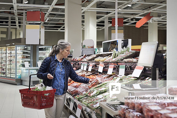 Reife Frau beim Gemüsekauf im Supermarkt