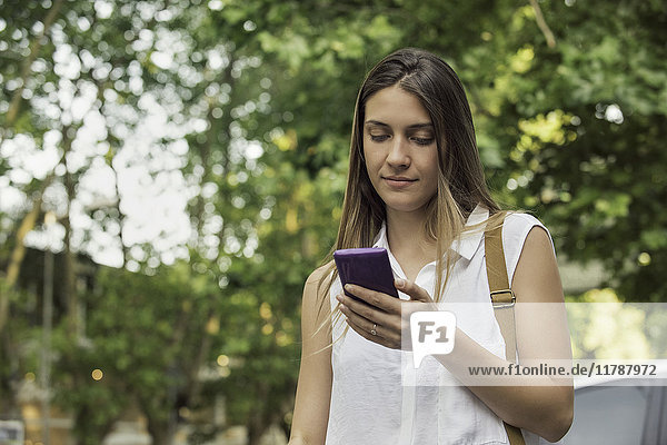 Junge Frau überprüft Smartphone im Freien