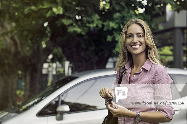 Junge Frau hält Autoschlüssel  lächelt fröhlich