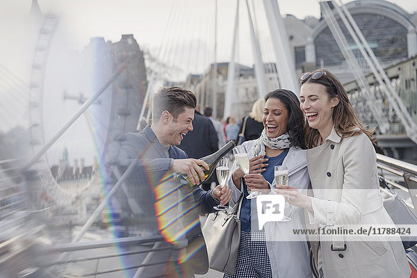 Lächelnde  glückliche Freunde beim Feiern  Champagner gießen in der Stadt  London  UK