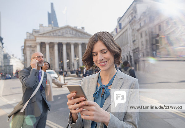Geschäftsfrau SMS mit Handy in der City Street, London, UK