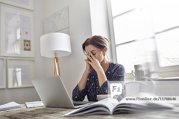 Müde  gestresste Geschäftsfrau am Laptop mit Kopf in den Händen
