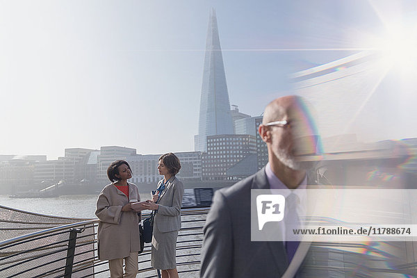 Geschäftsfrauen mit digitalem Tablett auf sonniger urbaner Brücke  London  UK