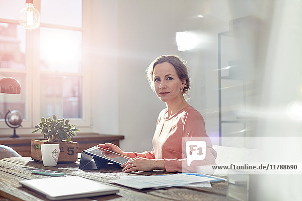 Porträtbewusste Geschäftsfrau mit digitalem Tablett am Schreibtisch im Büro