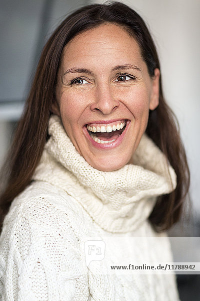 Porträt der lachenden reifen Frau mit weißem Strickpullover