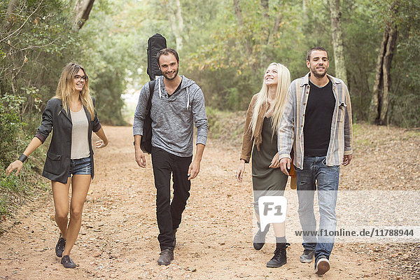 Four happy friends walking on path in the forest