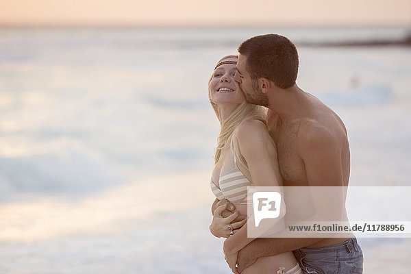 Romantisches Paar beim Küssen am Strand