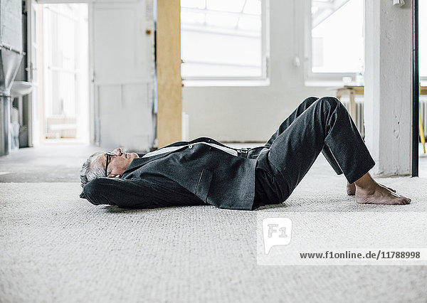 Senior Geschäftsmann auf dem Boden liegend