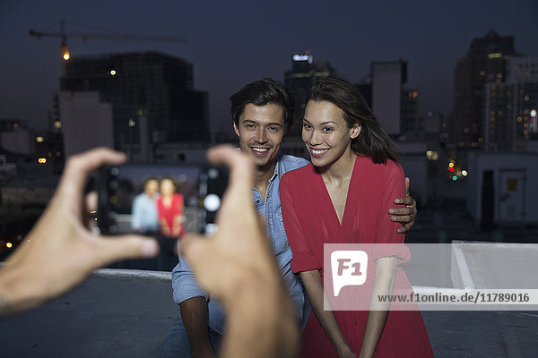 Young man taking picture of a couple at a rooftop party