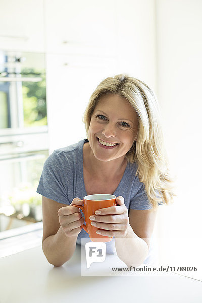 Porträt der lächelnden Frau zu Hause bei einer Tasse Kaffee