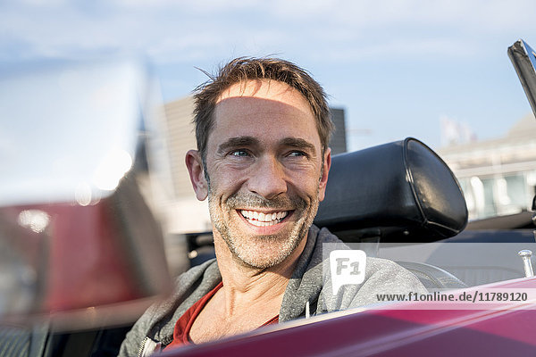 Portrait of smiling mature man sitting in his sports car