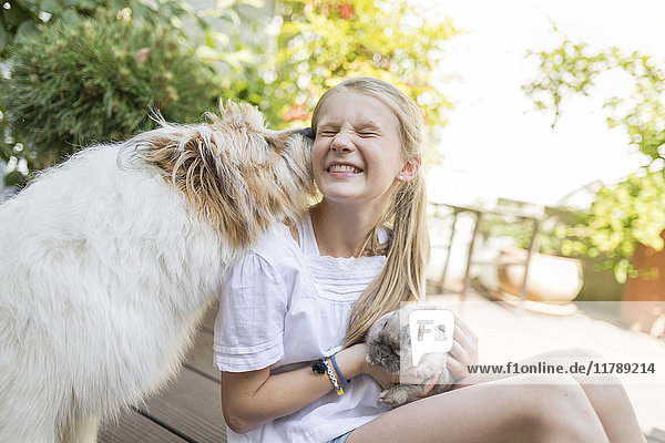Glückliches Mädchen mit Hase und Hund im Freien