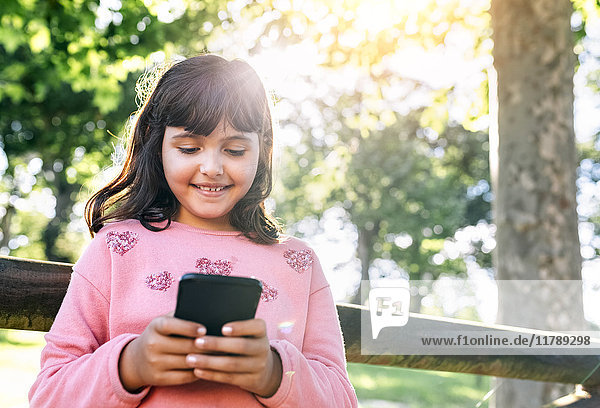 Lächelndes Mädchen sendet Nachrichten mit ihrem Smartphone