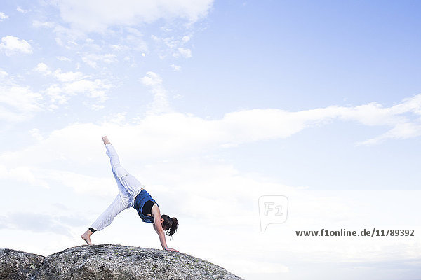 Frau bei einer Yoga-Übung auf einem Felsen